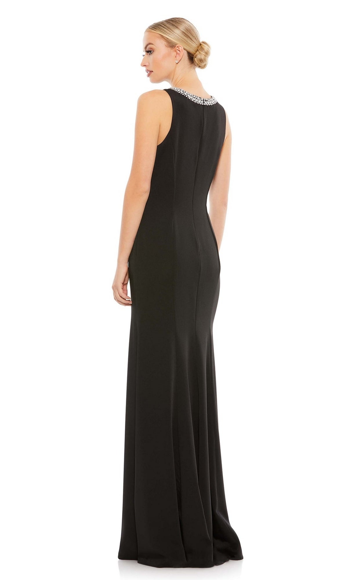 A woman stands facing away from the camera in the Mac Duggal 49093 Beaded-Neck Long Prom Dress, a sleeveless, floor-length black gown featuring a fitted silhouette and an embellished neckline.